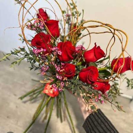 Dozen roses with filler and curly willow in the shape of a heart wrapped